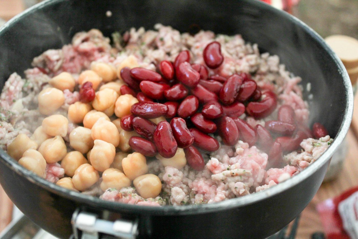 ひき肉の色が8割変わったら豆を入れます。